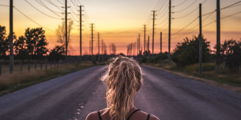 woman on road looking at utility poles and power lines