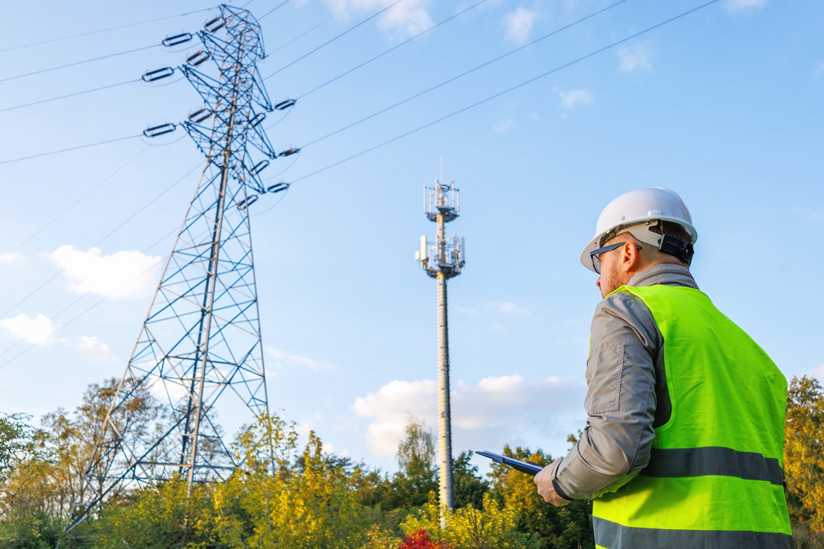 engineer inspecting telecom tower and power lines